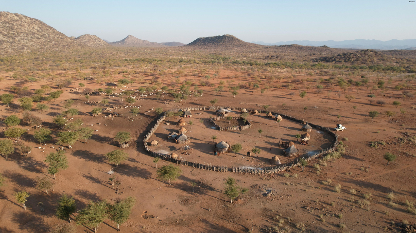 Aerial view of an NG3-area village, showing traditional huts arranged in a circular kraal within the dry Botswana landscape